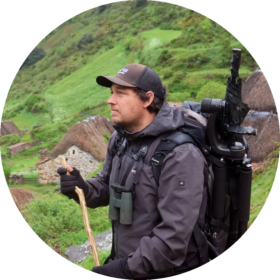 Romain Guerin, guide nature, devant des maisons en pierre aux toits de chaume.