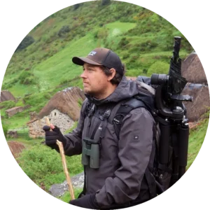 Romain Guerin, nature guide, beside stone houses with thatched roofs.